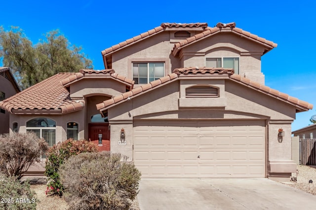 mediterranean / spanish-style home featuring a tile roof, stucco siding, concrete driveway, and a garage