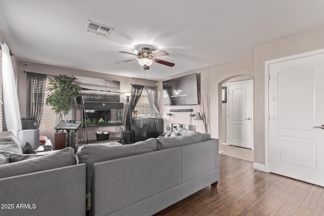 living area with wood finished floors, visible vents, arched walkways, and ceiling fan