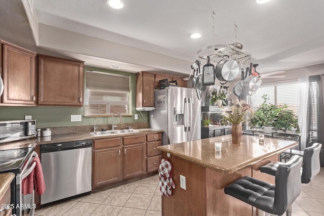 kitchen with a center island, brown cabinets, stainless steel appliances, and a sink