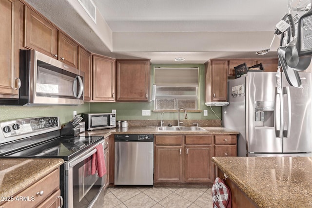 kitchen with visible vents, light tile patterned floors, brown cabinetry, stainless steel appliances, and a sink