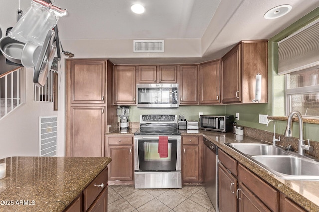 kitchen with visible vents, light tile patterned floors, appliances with stainless steel finishes, brown cabinetry, and a sink