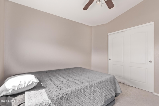 bedroom featuring a closet, light colored carpet, ceiling fan, and vaulted ceiling