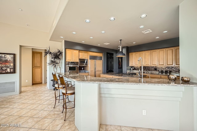 kitchen with kitchen peninsula, built in appliances, light stone counters, and hanging light fixtures