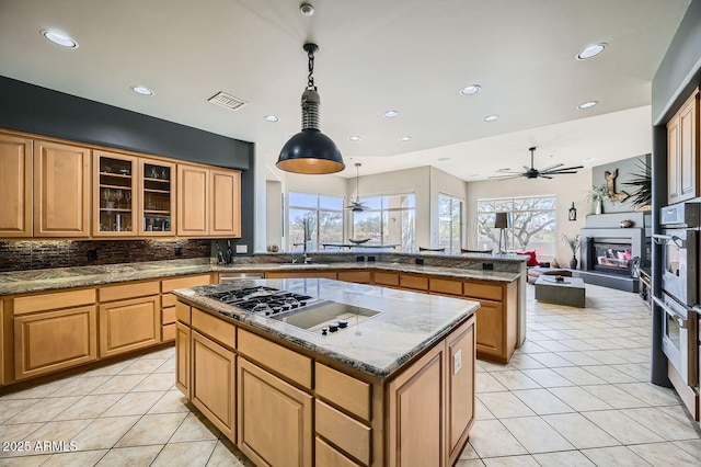 kitchen with pendant lighting, stainless steel gas stovetop, a center island, ceiling fan, and light tile patterned floors