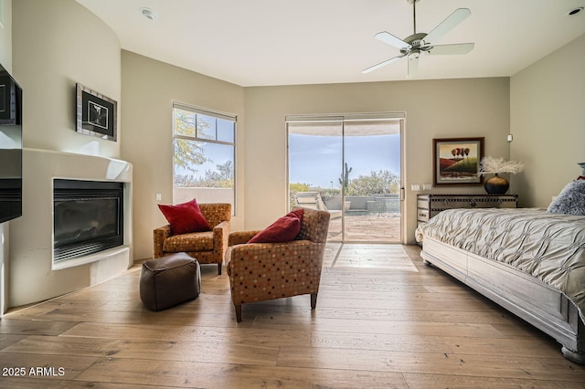 bedroom with access to exterior, hardwood / wood-style floors, multiple windows, and ceiling fan