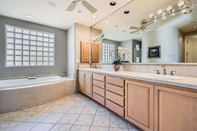 bathroom with tiled bath, tile patterned flooring, vanity, and a healthy amount of sunlight