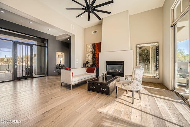 sitting room featuring ceiling fan, a large fireplace, and light wood-type flooring