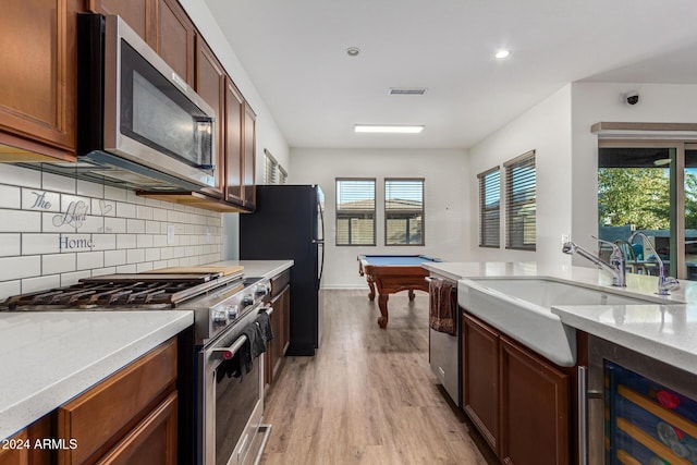 kitchen with decorative backsplash, appliances with stainless steel finishes, light wood-type flooring, beverage cooler, and pool table