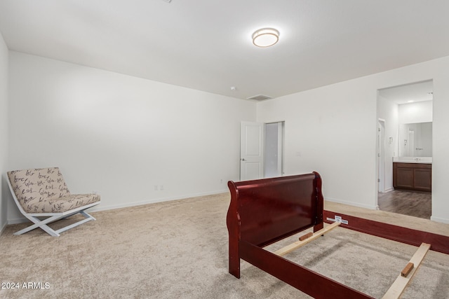 bedroom with connected bathroom and light carpet