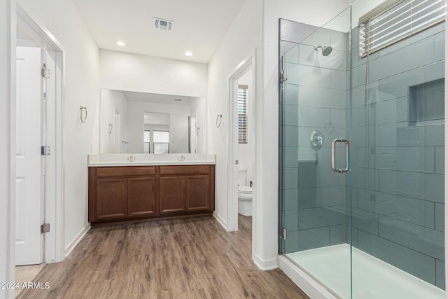 bathroom featuring vanity, toilet, wood-type flooring, and a shower with door