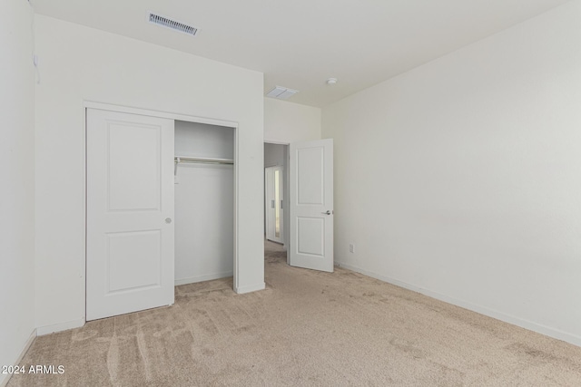 unfurnished bedroom with light carpet and a closet