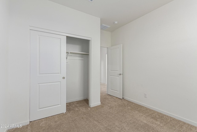 unfurnished bedroom featuring light carpet and a closet