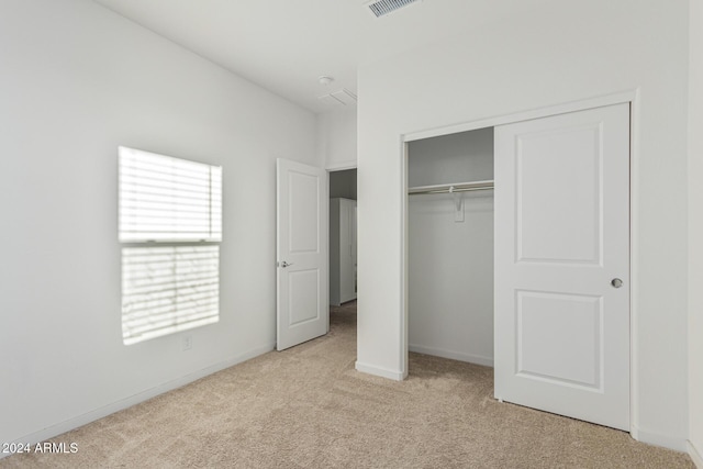 unfurnished bedroom featuring a closet and light colored carpet