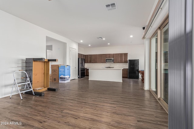 kitchen featuring black fridge, tasteful backsplash, a kitchen island, dark hardwood / wood-style flooring, and dark brown cabinetry