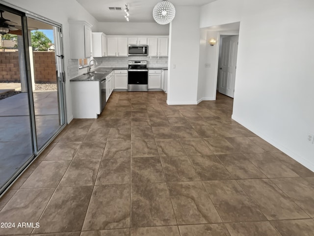 kitchen featuring dark tile floors, white cabinets, stainless steel appliances, sink, and tasteful backsplash