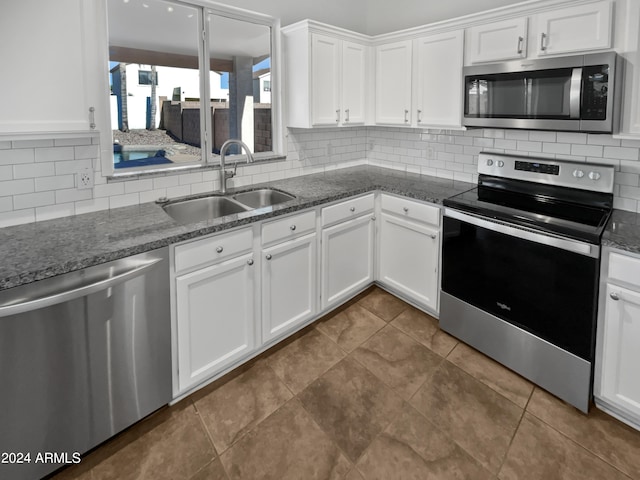 kitchen with tasteful backsplash, appliances with stainless steel finishes, white cabinetry, and sink