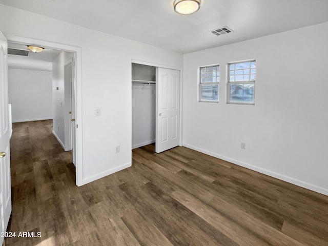 unfurnished bedroom with a closet and dark wood-type flooring