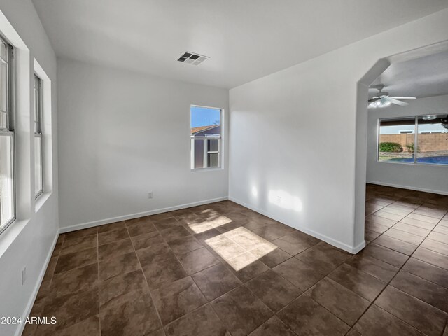 spare room featuring ceiling fan and dark tile floors