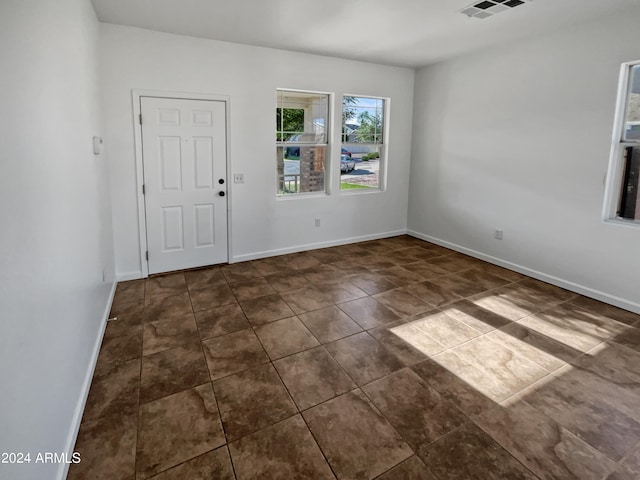 unfurnished room with dark tile floors