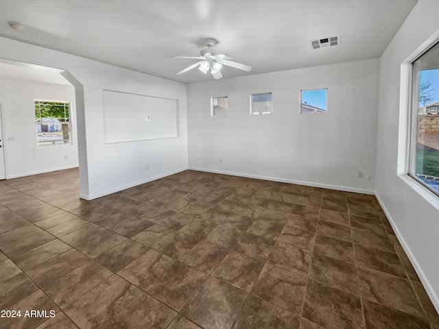 empty room featuring ceiling fan and dark tile floors