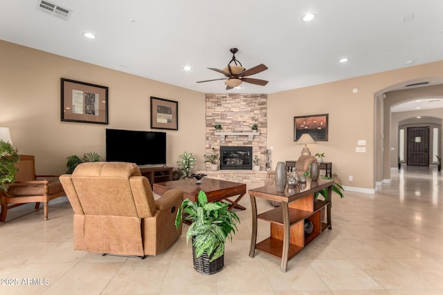 13336 W Via Caballo Blanco, Peoria, AZ 85383 - living room featuring a stone fireplace, light tile patterned floors, ceiling fan, arched walkways, and visible vents
