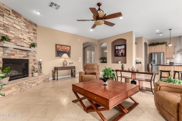 13336 W Via Caballo Blanco, Peoria, AZ 85383 - living room featuring arched walkways, visible vents, a ceiling fan, a stone fireplace, and light tile patterned floors
