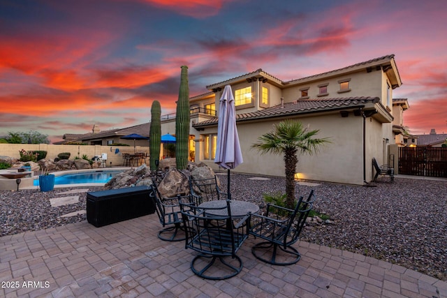13336 W Via Caballo Blanco, Peoria, AZ 85383 - back of property at dusk with a patio area, a fenced backyard, a tiled roof, and stucco siding