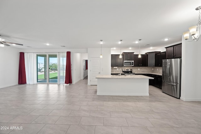 kitchen featuring a center island with sink, stainless steel appliances, hanging light fixtures, and tasteful backsplash