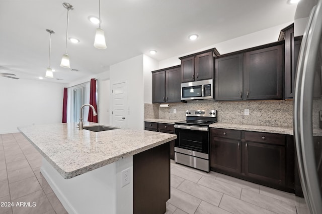 kitchen featuring backsplash, sink, stainless steel appliances, and an island with sink