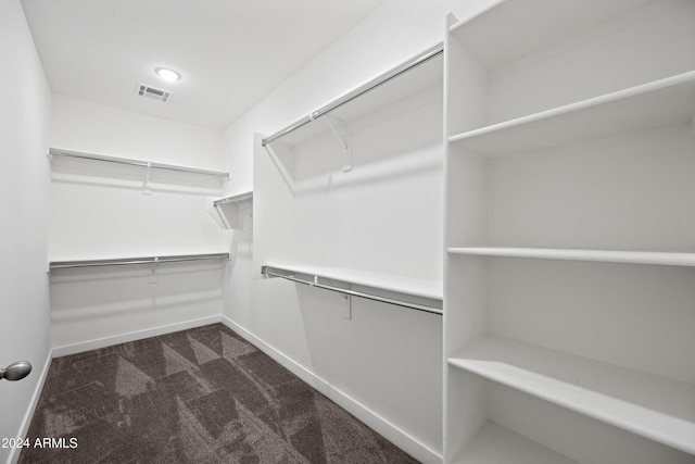 walk in closet with dark colored carpet