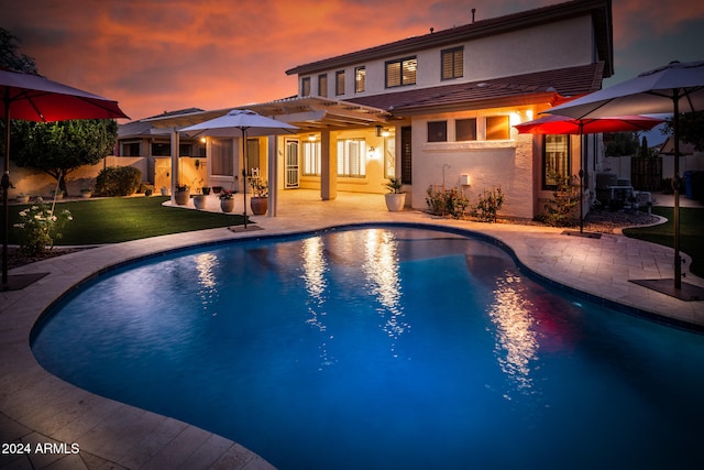 pool at dusk featuring a yard and a patio area