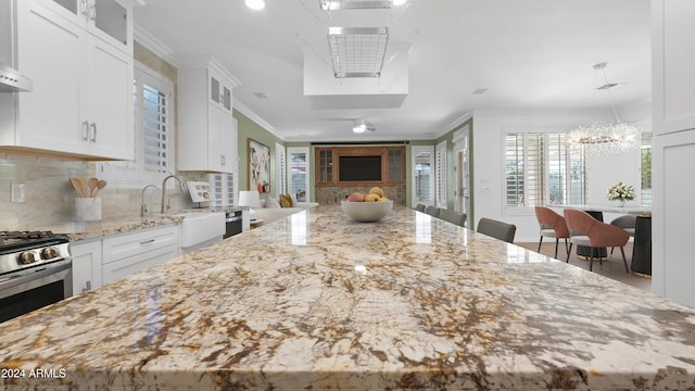 kitchen with white cabinets, a breakfast bar area, tasteful backsplash, crown molding, and light stone countertops