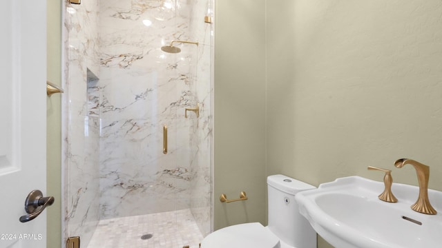 bathroom featuring a shower with door, sink, and toilet