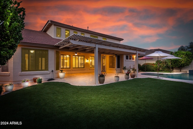 back house at dusk with a yard, a patio, and a pergola