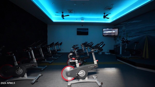 gym with ceiling fan and a tray ceiling