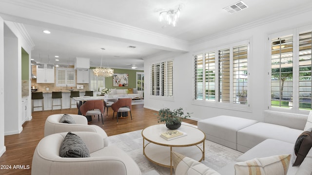 living room with a chandelier, light wood-type flooring, and crown molding