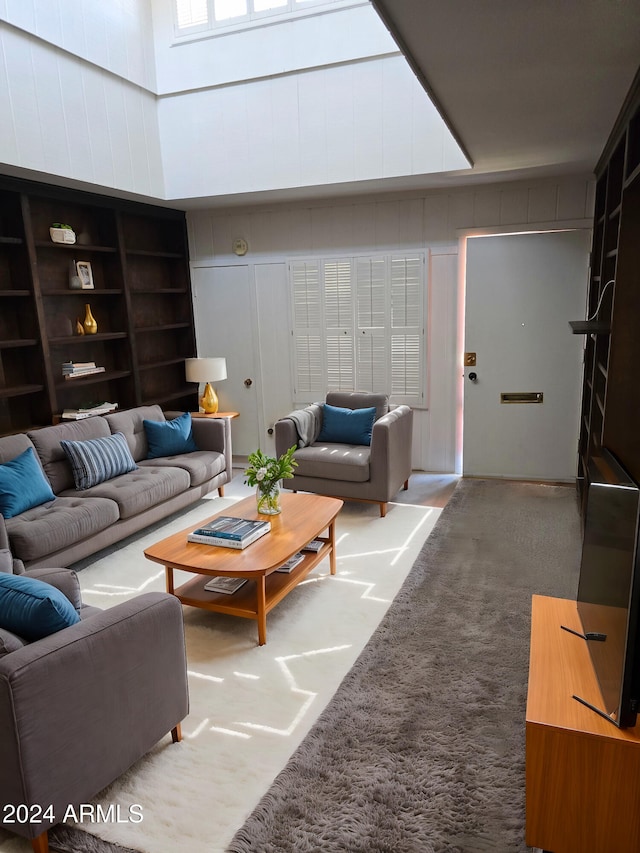 living room with built in shelves, a high ceiling, and carpet floors