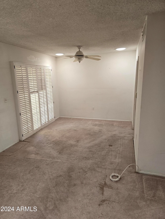 carpeted empty room with a textured ceiling and ceiling fan