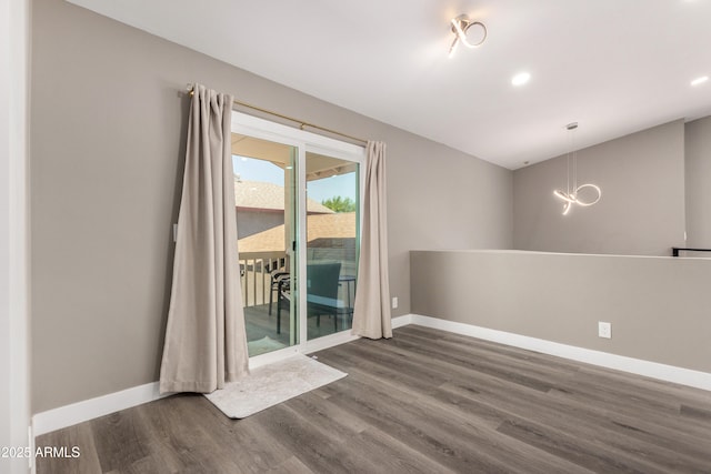 empty room featuring dark wood-style flooring, baseboards, recessed lighting, and a chandelier