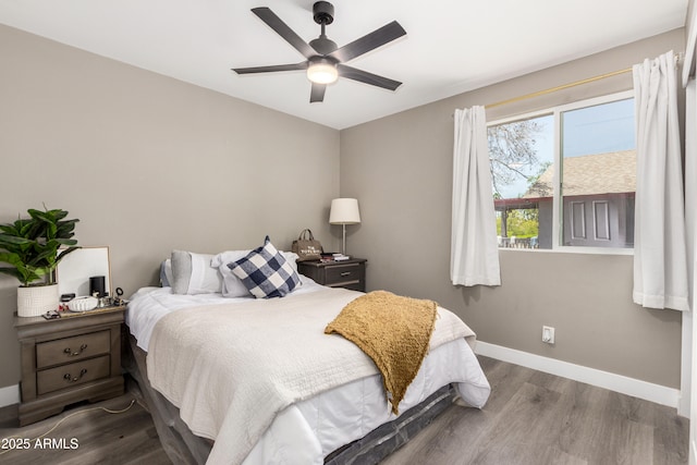 bedroom featuring baseboards, wood finished floors, and a ceiling fan