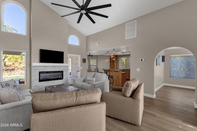 living room with light hardwood / wood-style flooring, high vaulted ceiling, and plenty of natural light