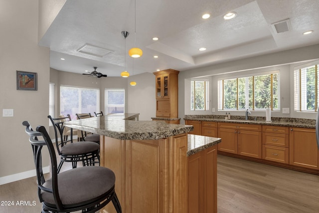 kitchen with a kitchen island, pendant lighting, a textured ceiling, light hardwood / wood-style floors, and ceiling fan