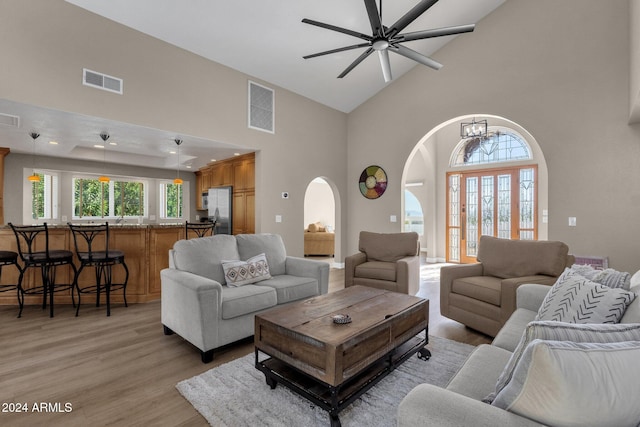 living room with light hardwood / wood-style flooring, high vaulted ceiling, and ceiling fan with notable chandelier