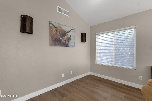 empty room with hardwood / wood-style floors and vaulted ceiling