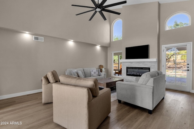 living room with ceiling fan, a healthy amount of sunlight, a high ceiling, and hardwood / wood-style floors