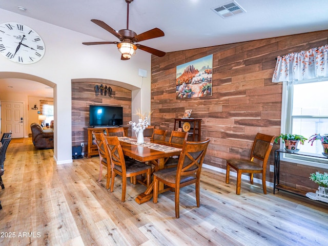 dining area with ceiling fan, wood walls, light wood-style floors, and visible vents