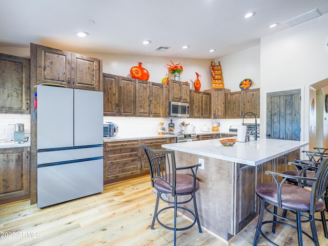 kitchen with tasteful backsplash, a breakfast bar area, appliances with stainless steel finishes, visible vents, and recessed lighting