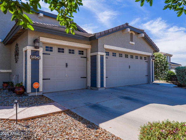 view of front facade with an attached garage, a tiled roof, driveway, and stucco siding