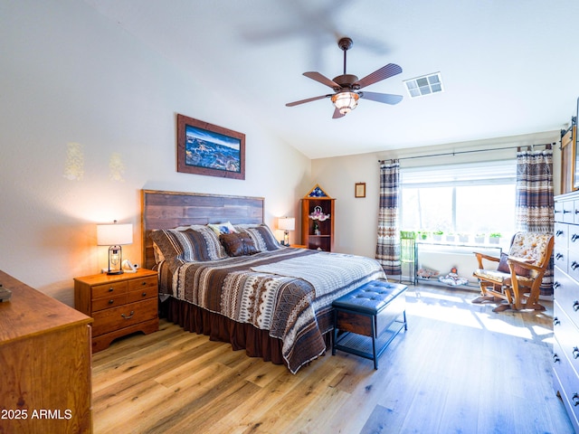 bedroom featuring light wood-style floors, vaulted ceiling, visible vents, and ceiling fan
