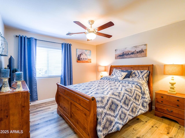 bedroom with light wood-type flooring, a ceiling fan, and baseboards